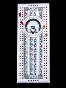 This wonderful two person and our two team cribbage boards is a beautiful accent piece for your home or take it on the road for use as a travel cribbage board.  With the magnet holding the center piece and pegs in place it is a stunning travel cribbage board. 

This is a stunning originally hand etched Claddagh Eco - Ivory Scrimshaw Cribbage Board!  The Claddagh Ring design is a traditional Irish design that represents love, loyalty, and friendship! The hands represent friendship, the heart represents love, and the crown represents loyalty. The center circular piece has a magnet holding it in place.  Pushing on the base of the piece pops the Large round off the board, where the pegs are stored.  All cribbage boards come with 3 red and 3 white/yellow wooden pegs. 

The cribbage board itself is made for two players or teams.  The board has a native geometric design that was originally hand etched.  The large round piece has a magnet on the back to keep it secured to the board and store the pegs.  The pegs are made of wood.  This is part of the Save the Elephant Collection and was originally hand etched by Linda Layden.  The SKU is NC 53 - 178.