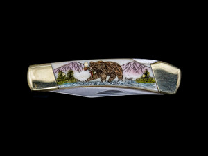 LB 5 102B Scrimshaw Collection Bear with Trout Pocket Knife.  This stunning hand etched Colored Bear eating a trout along a river design on a 440 Stainless Steel Blade LB 5 Knife.  This beautiful knife is part of the Scrimshaw Collection, with those words laser engraved into the blade.  The LB 5 knifes come with the pictured leather sheath and each scale is made with Bovine Bone.  The LB 5 Knife has bolsters and shackle that are nickel silver with brass pins and liner.  It is a lock blade knife and a very useful pocket knife. The dimensions of the LB 5 Pocket Knife with the blade closed are 3.71" x 0.90" x 0.39".  The blade itself is approximately 2.80" making the width of the knife with an open blade 6.51".  The SKU is LB-5 102B.

The scrimshaw is inked with colored india ink and sealed with renaissance wax, which is used by museums for antique restoration.  It also helps bring out the beauty of the artwork as well as in the cow bone. The knife is water resistant, but not waterproof.