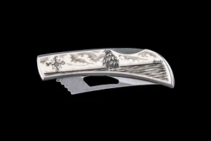 This unique originally hand etched Ship and Compass design on a Stainless Steel Silver Hawk Knife.  The back of the knife has a belt clip and all the knifes come with the pictured sheath.  It is a lock blade knife and a useful pocket knife.  The artwork was originally hand etched by Linda Layden.  The dimensions of the Silver Hawk knife with the blade closed are 3.00" x 0.96" x 0.55".  The blade itself is approximately 2.35" making the width of the knife with an open blade 5.35".  The SKU is NC 14 - 402.

Linda Layden has been making beautiful works of art in the scrimshaw field for over 40 years.  Originally a hobby that became a full time job.  Her work can be found in gift shops, galleries and museums across the world.