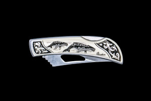 This beautiful originally hand etched Double Humpback Whale design on a Stainless Steel Silver Hawk Knife.  The back of the knife has a belt clip and all the knifes come with the pictured sheath.  It is a lock blade knife and a useful pocket knife. The artwork was originally hand etched by Linda Layden.  The dimensions of the Silver Hawk knife with the blade closed are 3.00" x 0.96" x 0.55".  The blade itself is approximately 2.35" making the width of the knife with an open blade 5.35".  The SKU is NC 14 - 100.

Linda Layden has been making beautiful works of art in the scrimshaw field for over 40 years.  Originally a hobby that became a full time job.  Her work can be found in gift shops, galleries and museums across the world.