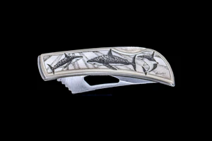 This beautiful originally hand etched Shark design on a Stainless Steel Silver Hawk Knife.  The back of the knife has a belt clip and all the knifes come with the pictured sheath.  It is a lock blade knife and a useful pocket knife. The artwork was originally hand etched by Linda Layden.  The dimensions of the Silver Hawk knife with the blade closed are 3.00" x 0.96" x 0.55".  The blade itself is approximately 2.35" making the width of the knife with an open blade 5.35".  The SKU is NC 14 - 267.

Linda Layden has been making beautiful works of art in the scrimshaw field for over 40 years.  Originally a hobby that became a full time job.  Her work can be found in gift shops, galleries and museums across the world.  

The resin scrimshaw piece is originally hand etched by Linda Layden.  We make a mold of the original piece and do an open cast pour of our resin mixture.  The pieces are removed from the mold and sanded and inked.

We believe that serving nature is one of the commissions that we as humans have been given here on earth.  We wish to lend our resources to those charged with protecting elephants from poaching for their ivory.