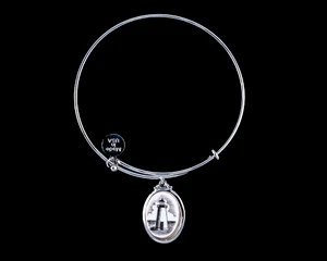 NC 07-820-S EtchedAdjustable Bracelets Neds Point Lighthouse Vertical Display.  The beautiful adjustable bracelet is decorated with a Vertical originally Hand etched Lighthouse Charm.  The product ID is NC 07-820-SE.  The design of the Lighthouse, is that of Ned's Point which is located in Mattapoisett, MA.  

This bracelet is a one size for most, with an adjustable wire band.  Each bracelet can be customized with different unique charms to attach.  All parts are made in the USA!.

The Eco-Ivory Scrimshaw Charm is 13x18.  The artwork was originally hand etched by Linda Layden.

Linda Layden has been making beautiful works of art in the scrimshaw field for over 40 years.  Originally a hobby that became a full time job.  Her work can be found in gift shops, galleries and museums across the world.  

We make a mold of the original piece and do an open cast pour of our resin mixture.  The pieces are removed from the mold and sanded and inked.