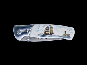 This absolutely gorgeous hand etched Ship and Lighthouse design on a Buck 835 Folding Selkirk Pocket Knife with a bovine bone front handle.  The back of the knife has a belt clip/ money clip.  It is a lock blade knife and a useful pocket knife.  The artwork was originally hand etched by Bill Feeney.  The knife is a liner lock blade, meaning it was made for one handed opening.  The dimensions of the Buck 835 Folding Selkirk Pocket Knife with the blade closed are 4.29" x 1.23" x 0.60".  The blade itself is approximately 3.25" making the width of the knife with an open blade 7.5".  The SKU is NC 835 - 406C.

This unique etching has a colored Ship and Lighthouse scene!

The artwork was originally hand etched by Bill Feeney. He received a Bachelor of Arts degree in Mathematics from Saint Francis College in Bidderford, Maine, In 1973 I accepted a teaching position at Westport High School where I met Robert Rayno, the art teacher. As part of the class curriculum, he taught a section on scrimshaw. I sat in on many of his classes and purchased the necessary tools and ivory to begin etching. Combining my natural artistic ability with the techniques learned from Mr. Rayno, the cornerstone of "Spouting Whale" was established.

The scrimshaw is inked with a colored india ink and sealed with renaissance wax, which is used by museums for antique restoration.  It also helps bring out the beauty of the artwork as well as in the cow bone. The knife is water resistant, but not waterproof.

Buck 420HS Steel.  This is Buck's standard blade material because it approaches the wear resistance of high carbon alloys while delivering the corrosion resistance of chromium steels.  Add in Buck's exclusive heat-treat process for durability and corrosion resistance.

Drop Point Blade, is full bellied with a strong thick point for heavier tasks.  The drop point blade is strong and versatile.