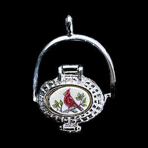 This is a incredibly detailed Sterling Silver Nantucket Basket Pendant with a replica scrimshaw with a Cardinal design.  Inside the basket is a mini penny.  The basket on it's own has the following dimensions, .78"x .48"x .77".  The pendant holder add .22" x .85".  Each pendant weighs .31 ounces.  All the pendants come with an 18" gold chain. The item number is SNB 115.

This Nantucket Lightship basket pendant is made in pewter and was plated in Sterling Silver.  These beautiful baskets are similar to what is seen on the Netflix hit, Sirens

Nantucket lightship baskets, characterized by their rattan staves, cane weavers, and wooden bases, originated on the island's lightships in the mid-1800s. Initially, these baskets were a way for lightship crewmen to pass the time during long deployments and were primarily utilitarian. Over time, the baskets evolved, becoming more refined and sought after as souvenirs of Nantucket.

Keeping with the tradition of a penny in the basket.  A penny is placed inside the basket to symbolize good luck.  Each of our basket pendants have a mini penny inside to carry on the tradition.  

Linda Layden has been making beautiful works of art in the scrimshaw field for over 40 years.  Originally a hobby that became a full time job.  Her work can be found in gift shops, galleries and museums across the world.  

The resin scrimshaw piece is originally hand etched by Linda Layden.  We make a mold of the original piece and do an open cast pour of our resin mixture.  The pieces are removed from the mold and sanded and inked with Indian Ink.

We believe that serving nature is one of the commissions that we as humans have been given here on earth.  We wish to lend our resources to those charged with protecting elephants from poaching.

On a monthly basis we donate to organizations whose purpose to protect the elephants and other species throughout the planet.  We focus our donations on organizations that put the money to good use and have a low overhead. With the majority of incoming funds going back to saving the elephants!

American Made
Nantucket Basket Pendant
Sterling Silver Plated
Pewter Base 
Mini Penny
18" Silver Chain
Bird Design
Cardinal
Resin Scrimshaw Design Top
Lifetime Guarantee