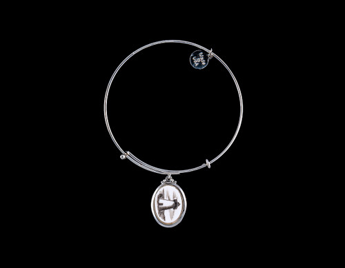 NC 07 820 SE Adjustable Bracelet  Display.  The beautiful adjustable bracelet is decorated with Scrimshaw Lighthouse Charm.  The product ID is NC 07-820-SE.  The design of the Lighthouse, is that of Ned's Point which is located in Mattapoisett, MA.  

This bracelet is a one size for most, with an adjustable wire band.  Each bracelet can be customized with different unique charms to attach.  All parts are made in the USA!.

The Eco-Ivory Scrimshaw Charm is 13x18.  The artwork was originally hand etched by Linda Layden.

Linda Layden has been making beautiful works of art in the scrimshaw field for over 40 years.  Originally a hobby that became a full time job.  Her work can be found in gift shops, galleries and museums across the world.  

We make a mold of the original piece and do an open cast pour of our resin mixture.  The pieces are removed from the mold and sanded and inked.