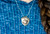 Pendant Sample.  This is a beautiful originally hand etched Squirrel designed pin/pendant.  The unique shape of the piece is an Acorn Nut. The backing of this piece has the findings to be a pin, as well as a pendant.  They come with an 18" Silver Plated Chain.  This is part of the incredible line of Mossup Valley Designs that we carry, with the wonderful artist Rachel Badeau.  The dimensions of the necklace are 1.44" x 1.68" x 0.48".  The SKU is MVD PN 8.

Rachel Badeau has been etching and engraving in a variety of media for over thirty years.  Her work, characterized by fine line and intricate detail, attempts to touch the hearts and emotions of others.  All while reflecting her love of animals, nature and the human spirit.  

The resin scrimshaw piece is originally hand etched by Rachel Badeau.  We make a mold of the original piece and do an open cast pour of our resin mixture.  The pieces are removed from the mold and sanded and inked.
