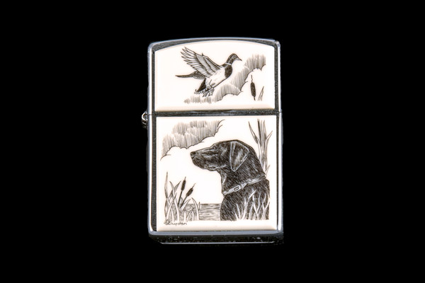 This is a unique originally hand etched Eco-Ivory Black Lab designed Zippo Lighter! The top of the flip lighter has a a Duck flying away.   The Zippo is a Brushed Chrome finish. Each lighter has a bottom stamp signifying the year it was made, is refillable. All windproof lighters are American made in Bradford, PA factory and come packaged in a gift box.  This is part of the Save the Elephant Collection and was originally hand etched by Linda Layden. The SKU is NC 54 - 142

The Zippo Lighter is 2.24" x 1.51" x 0.59".  It weighs 2.04 oz.