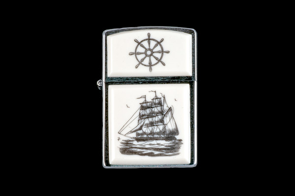 This is a unique Nautical Style Eco-Ivory Scrimshaw Charles W. Morgan Ship designed Zippo Lighter! The top of the flip lighter has a Ship Wheel design.  The Zippo is a Brushed Chrome finish. Each lighter has a bottom stamp signifying the year it was made, is refillable. All windproof lighters are American made in Bradford, PA factory and come packaged in a gift box.  This is part of the Save the Elephant Collection and was originally hand etched by Bill Feeney. The SKU is NC 54 - 451.

The Zippo Lighter is 2.24" x 1.51" x 0.59".  It weighs 2.04 oz.

Charles W. Morgan is an American whaling ship built in 1841 that was active during the 19th and early 20th centuries. Ships of this type were used to harvest the blubber of whales for whale oil which was commonly used in lamps. Charles W. Morgan has served as a museum ship since the 1940s and is now an exhibit at the Mystic Seaport museum in Mystic, Connecticut. She is the world's oldest surviving merchant vessel and the only surviving wooden whaling ship from the 19th century American merchant fleet. The Morgan was designated a National Historic Landmark in 1966!