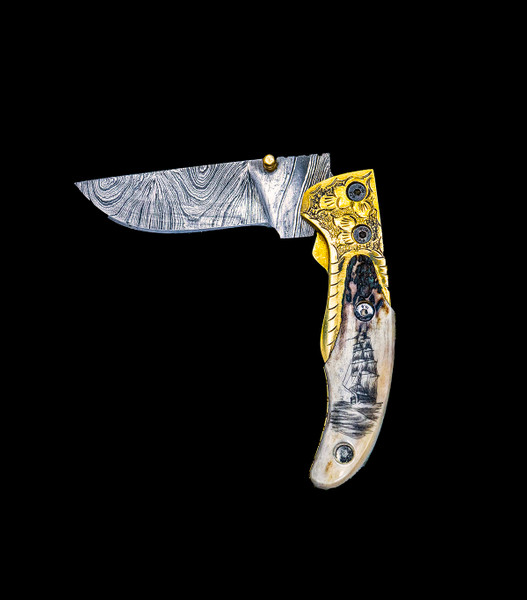 This beautiful vertical etched Ship design Shed Moose Antler handle with a lock damascus blade.  The knife itself is a single blade liner lock damascus blade knife.  It has fancy brass bolsters and a brass finger knob for easy opening.

The artwork was originally hand etched by Bill Feeney. He received a Bachelor of Arts degree in Mathematics from Saint Francis College in Bidderford, Maine, In 1973 I accepted a teaching position at Westport High School where I met Robert Rayno, the art teacher. As part of the class curriculum, he taught a section on scrimshaw. I sat in on many of his classes and purchased the necessary tools and ivory to begin etching. Combining my natural artistic ability with the techniques learned from Mr. Rayno, the cornerstone of "Spouting Whale" was established.

The weight of the knife is 5.39 ounces and the dimensions of the DM 003 Knife closed are 4.02" x 1.3" x 0.75".  The blade itself is approximately 3.18" making the knife 7.2" with the knife blade open.  The SKU is DM 003 401.  During the winter season, moose shed their antlers before regrowing them in the spring. The shedding process, also known as casting, is a normal event that occurs annually for many male cervids—a group of hoofed mammals like moose, deer and elk.

Damascus steel is a type of steel easily recognisable by its wavy patterned design. Aside from its sleek look and beautiful aesthetics, Damascus steel is highly valued as it is hard and flexible while maintaining a sharp edge. Weapons forged from Damascus steel were far superior to those formed from just iron.  It a combination of carbon steel and regular steel that is folded 71 times.  

Features:
Shed Antler Handle
Scrimshaw
Etched
Nautical Design
Tall Ship
Pocket Knife

Liner Lock
Brass Bolsters
Brass Finger knob
Damascus Blade

Carbon and regular Steel
Folded 71 times