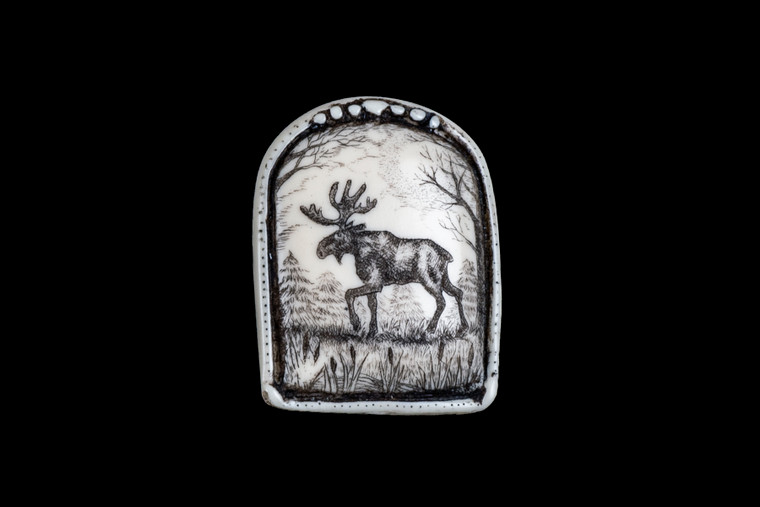 This is a beautiful originally hand etched Moose designed pin/pendant. The backing of this piece has the findings to be a pin, as well as a pendant.  They come with an 18" Silver Plated Chain.  This is part of the incredible line of Mossup Valley Designs that we carry, with the wonderful artist Rachel Badeau.  The dimensions of the necklace are 1.16" x 1.48" x 0.32".  The SKU is MVD PN 20.

Rachel Badeau has been etching and engraving in a variety of media for over thirty years.  Her work, characterized by fine line and intricate detail, attempts to touch the hearts and emotions of others.  All while reflecting her love of animals, nature and the human spirit.  

The resin scrimshaw piece is originally hand etched by Rachel Badeau.  We make a mold of the original piece and do an open cast pour of our resin mixture.  The pieces are removed from the mold and sanded and inked.