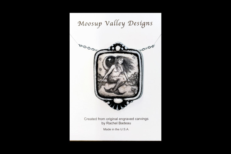 MVD PN 6 Mermaid Carded.  This is a beautiful originally hand etched Mermaid designed pin/pendant. The backing of this piece has the findings to be a pin, as well as a pendant.  They come with an 18" Silver Plated Chain.  This is part of the incredible line of Mossup Valley Designs that we carry, with the wonderful artist Rachel Badeau.  The dimensions of the necklace are 1.27" x 1.74" x 0.34".  The SKU is MVD PN 6.

Rachel Badeau has been etching and engraving in a variety of media for over thirty years.  Her work, characterized by fine line and intricate detail, attempts to touch the hearts and emotions of others.  All while reflecting her love of animals, nature and the human spirit.  

The resin scrimshaw piece is originally hand etched by Rachel Badeau.  We make a mold of the original piece and do an open cast pour of our resin mixture.  The pieces are removed from the mold and sanded and inked.