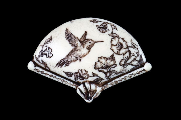 MVD PN 28 Zoom.  This distinct originally hand etched Hummingbird designed pin/pendant. The backing of this piece has the findings to be a pin, as well as a pendant.  They come with an 18" Silver Plated Chain.  This is part of the incredible line of Mossup Valley Designs that we carry, with the wonderful artist Rachel Badeau.  The dimensions of the necklace are 1.71" x 1.17" x 0.40".  The SKU is MVD PN 28.

Rachel Badeau has been etching and engraving in a variety of media for over thirty years.  Her work, characterized by fine line and intricate detail, attempts to touch the hearts and emotions of others.  All while reflecting her love of animals, nature and the human spirit.  

The resin scrimshaw piece is originally hand etched by Rachel Badeau.  We make a mold of the original piece and do an open cast pour of our resin mixture.  The pieces are removed from the mold and sanded and inked.
