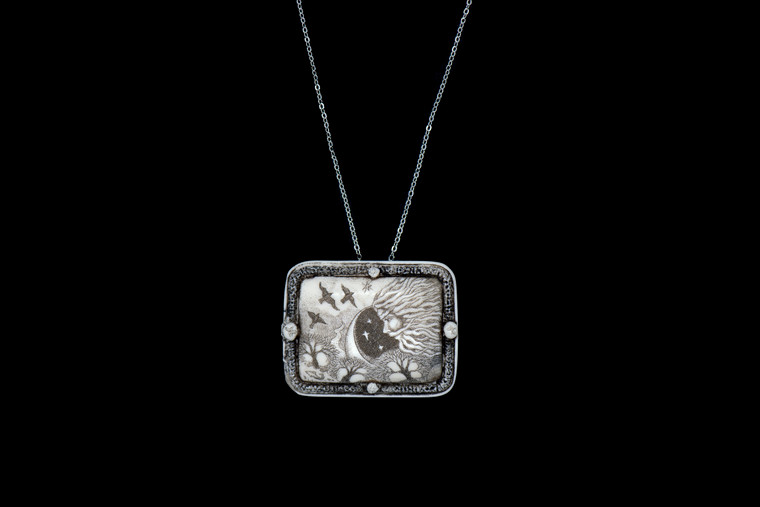 MVD PN 49 North Wind Necklace.  This distinct originally hand etched North Wind designed pin/pendant.  They come with an 18" Silver Plated Chain.  This is part of the incredible line of Mossup Valley Designs that we carry, with the wonderful artist Rachel Badeau.  The dimensions of the necklace are 1.80" x 1.41" x 0.37".  The SKU is MVD PN 48.

Rachel Badeau has been etching and engraving in a variety of media for over thirty years.  Her work, characterized by fine line and intricate detail, attempts to touch the hearts and emotions of others.  All while reflecting her love of animals, nature and the human spirit.  

The resin scrimshaw piece is originally hand etched by Rachel Badeau.  We make a mold of the original piece and do an open cast pour of our resin mixture.  The pieces are removed from the mold and sanded and inked.