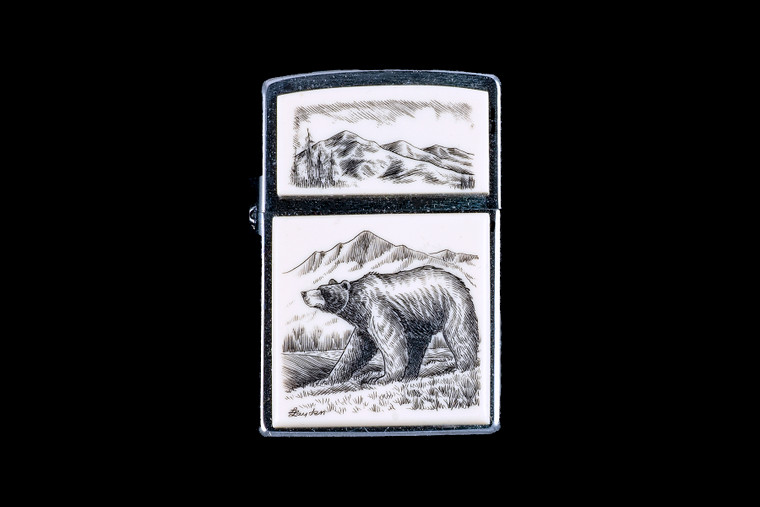 This is a beautiful originally hand etched Eco-Ivory Scrimshaw Bear designed Zippo Lighter! The top of the flip lighter has a a Mountain Skyline Top piece.  The Zippo is a Brushed Chrome finish. Each lighter has a bottom stamp signifying the year it was made, is refillable. All windproof lighters are American made in Bradford, PA factory and come packaged in a gift box.  This is part of the Save the Elephant Collection and was originally hand etched by Linda Layden. The SKU is NC 54 - 131.

The Zippo Lighter is 2.24" x 1.51" x 0.59".  It weighs 2.04 oz.