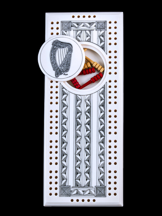 This wonderful two person and our two team cribbage boards is a beautiful accent piece for your home or take it on the road for use as a travel cribbage board.  With the magnet holding the center piece and pegs in place it is a stunning travel cribbage board. 

This is a beautiful originally hand etched Celtic Harp Eco - Ivory Scrimshaw Cribbage Board!   The center circular piece has a magnet holding it in place.  Pushing on the base of the piece pops the Large round off the board, where the pegs are stored.  All cribbage boards come with 3 red and 3 white/yellow wooden pegs. 

The cribbage board itself is made for two players or teams.  The board has a native geometric design that was originally hand etched.  The large round piece has a magnet on the back to keep it secured to the board and store the pegs.  The pegs are made of wood.  This is part of the Save the Elephant Collection and was originally hand etched by Linda Layden.  The SKU is NC 53 - 177.