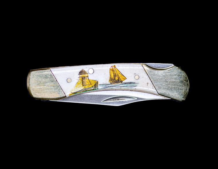 This beautiful hand etched Classic Colored Inked Ship and Lighthouse design on a 440 Stainless Steel Blade LB 5 Knife.  This beautiful knife is part of the Scrimshaw Collection, with those words laser engraved into the blade.  The LB 5 knifes come with the pictured leather sheath and each scale is made with Bovine Bone.  The LB 5 Knife has bolsters and shackle that are nickel silver with brass pins and liner.  It is a lock blade knife and a very useful pocket knife. The dimensions of the LB 5 Pocket Knife with the blade closed are 3.71" x 0.90" x 0.39".  The blade itself is approximately 2.80" making the width of the knife with an open blade 6.51".  The SKU is LB-5 401CY.

The scrimshaw is inked with colored india ink and sealed with renaissance wax, which is used by museums for antique restoration.  It also helps bring out the beauty of the artwork as well as in the cow bone. The knife is water resistant, but not waterproof.