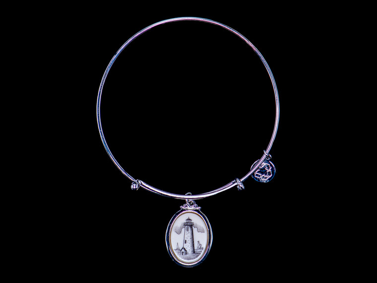 Nc 07 435 SEV Great Point Light Adjustable Bracelet Display.   The beautiful adjustable bracelet is decorated with Scrimshaw Lighthouse Charm.  The product ID is NC 07-435-SEVC.  The design of the Lighthouse, is that of Great Point Lighthouse which is located in Nantucket, MA.  

This bracelet is a one size for most, with an adjustable wire band.  Each bracelet can be customized with different unique charms to attach.  All parts are made in the USA!.

The Eco-Ivory Scrimshaw Charm is 13x18.  The artwork was originally hand etched by Linda Layden.

Linda Layden has been making beautiful works of art in the scrimshaw field for over 40 years.  Originally a hobby that became a full time job.  Her work can be found in gift shops, galleries and museums across the world.  

We make a mold of the original piece and do an open cast pour of our resin mixture.  The pieces are removed from the mold and sanded and inked.

We believe that serving nature is one of the commissions that we as humans have been given here on earth.  We wish to lend our resources to those charged with protecting elephants from poaching for their ivory.