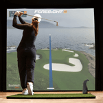 Golfer swinging in front of the Foresight simulator screen.
