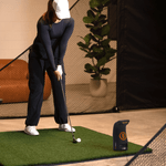 Player addressing the ball with Bushnell Launch Pro on turf mat.