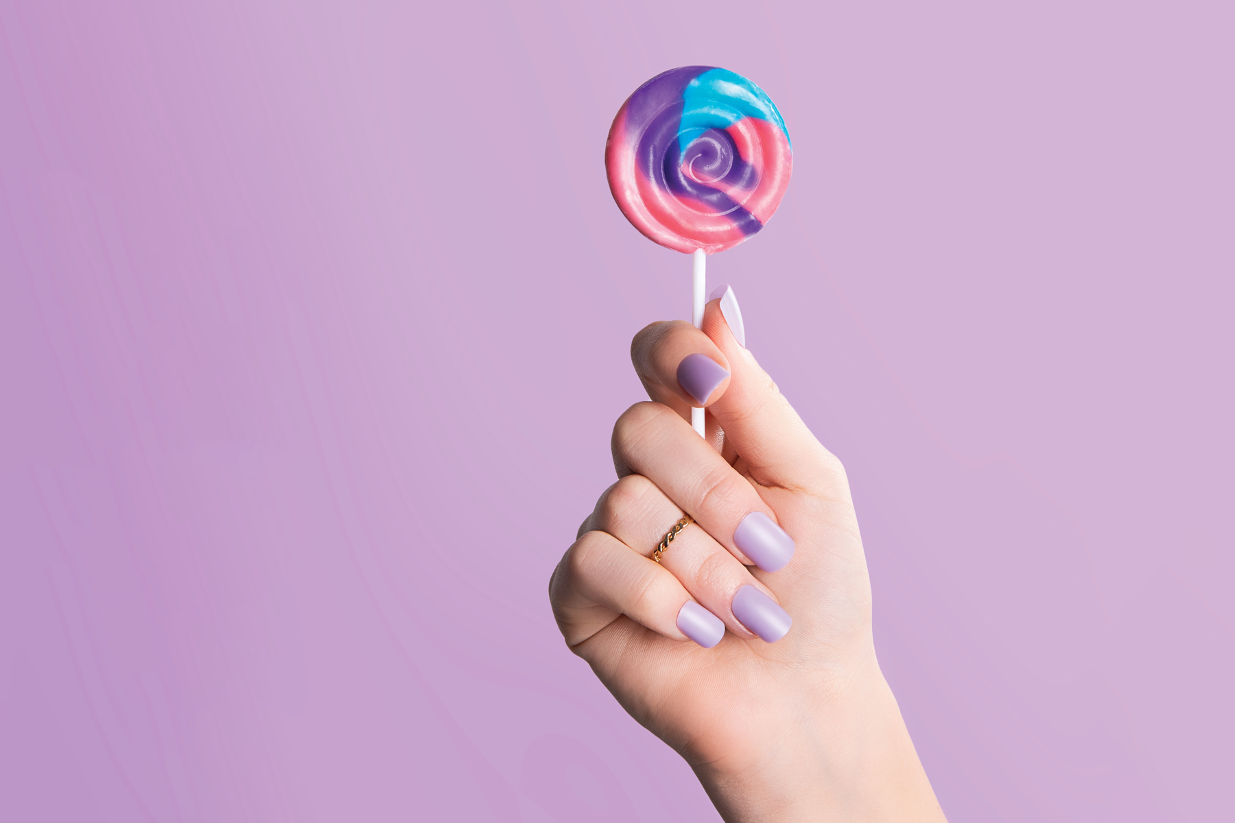 hand with purple color changing press on nails holding a lollipop 