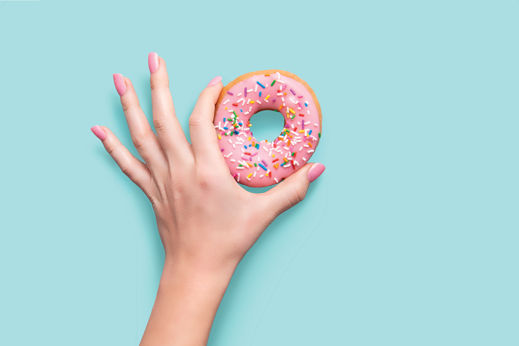 color changing press on nails and a hand holding a pink frosted donut
