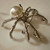 Alloy metal, synthetic pearl brooch or charm. 1.5' x 2'
Spiders represent balance, intuition, and the intricate connections between fate and free will.