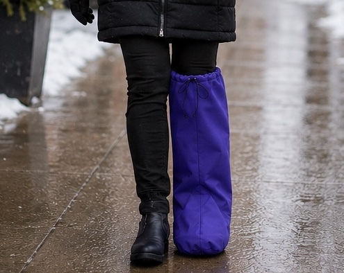 woman wearing boots and a castcoverz boot cast cover standing on a sidewalk in the snow