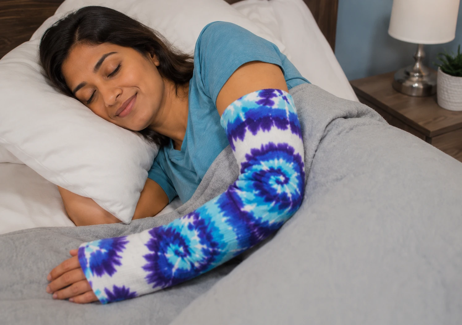 Woman sleeping comfortably while wearing a colorful tie-dye arm cast cover
