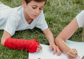 Kids’ Confidence: Child wearing a colorful red arm cast while playing outdoors with friends