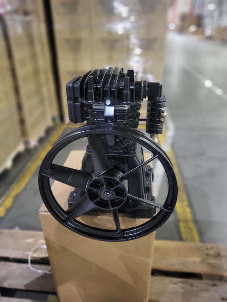 Hitachi 888839 Air Compressor Pump Replacement, Complete Assembly, Single-Stage, 5.5 HP - Front view of the black compressor pump with cooling fins and a pulley on a cardboard box in a warehouse.