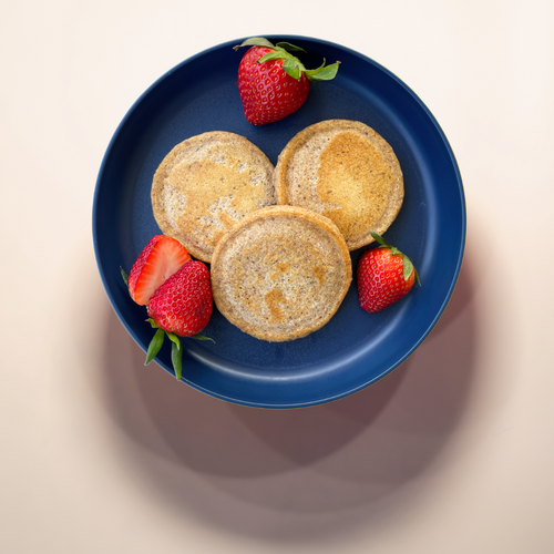 Stack of pancakes with strawberries on a dark blue plate