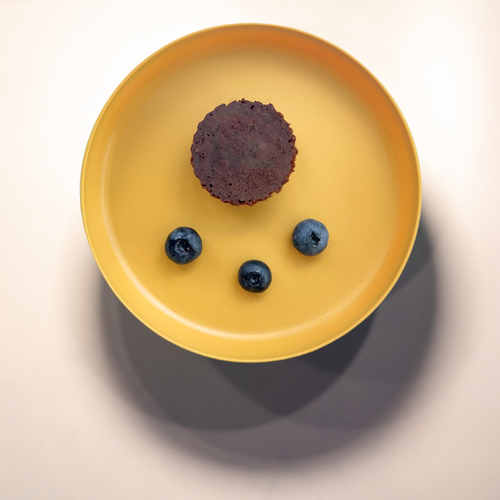 Cocoa cake with blueberries on a yellow plate