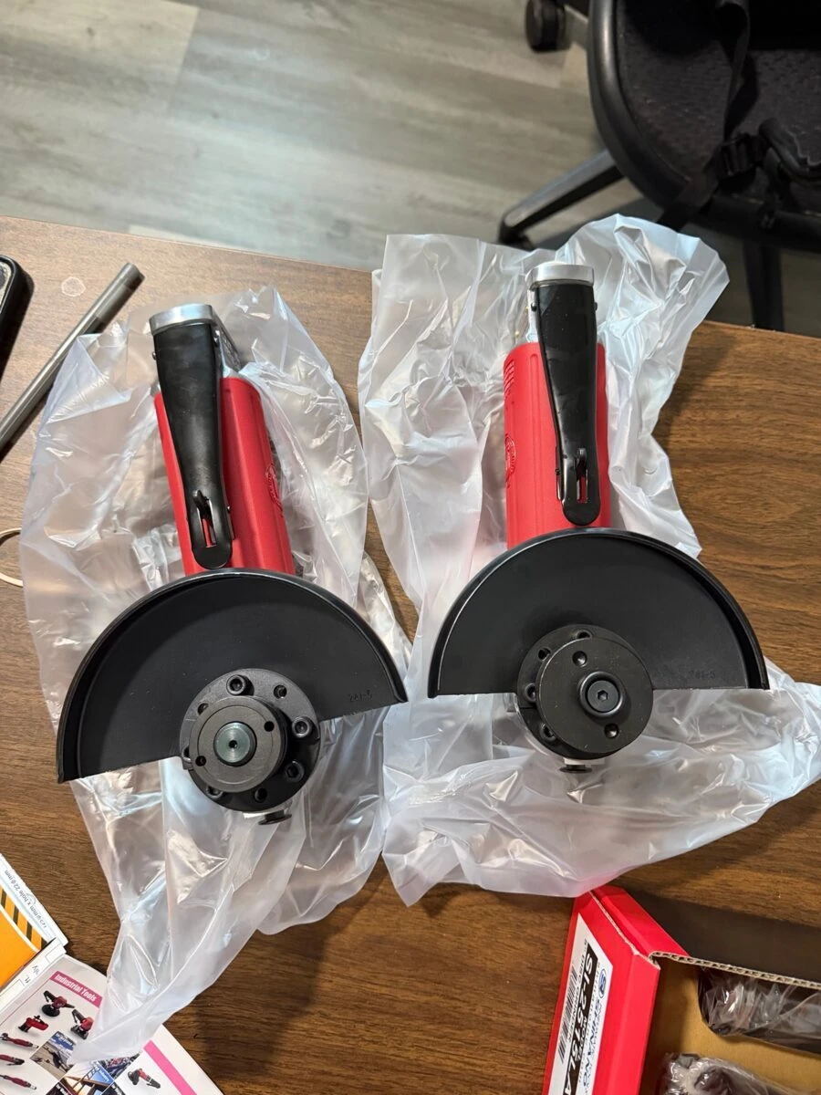 Tend-supplied photograph of two red pneumatic grinders with guards and exposed wheel mounting assemblies