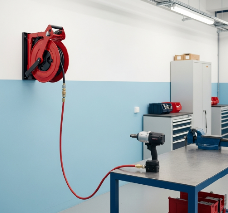 Automotive workshop air hose reel delivering compressed air to a pneumatic impact wrench