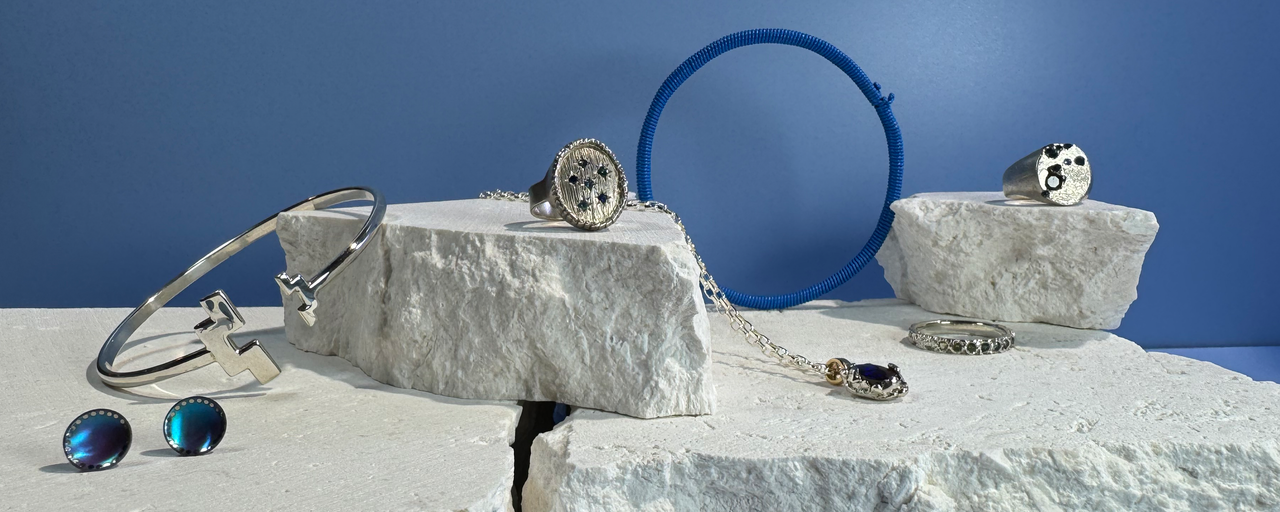 A collection of blue toned jewellery sitting atop white rock against a blue background.