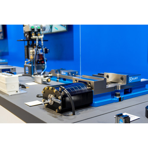 Kurt DX6A pneumatic vise with blue base, silver jaws, and attached black pneumatic cylinder mounted on a workbench