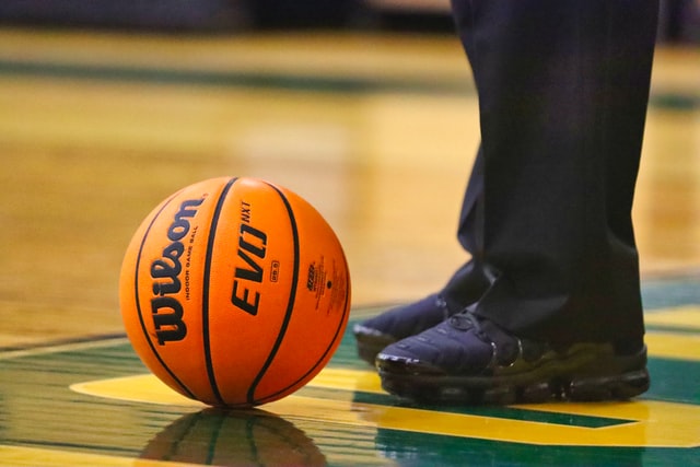 A basketball next to a basketball official’s shoes