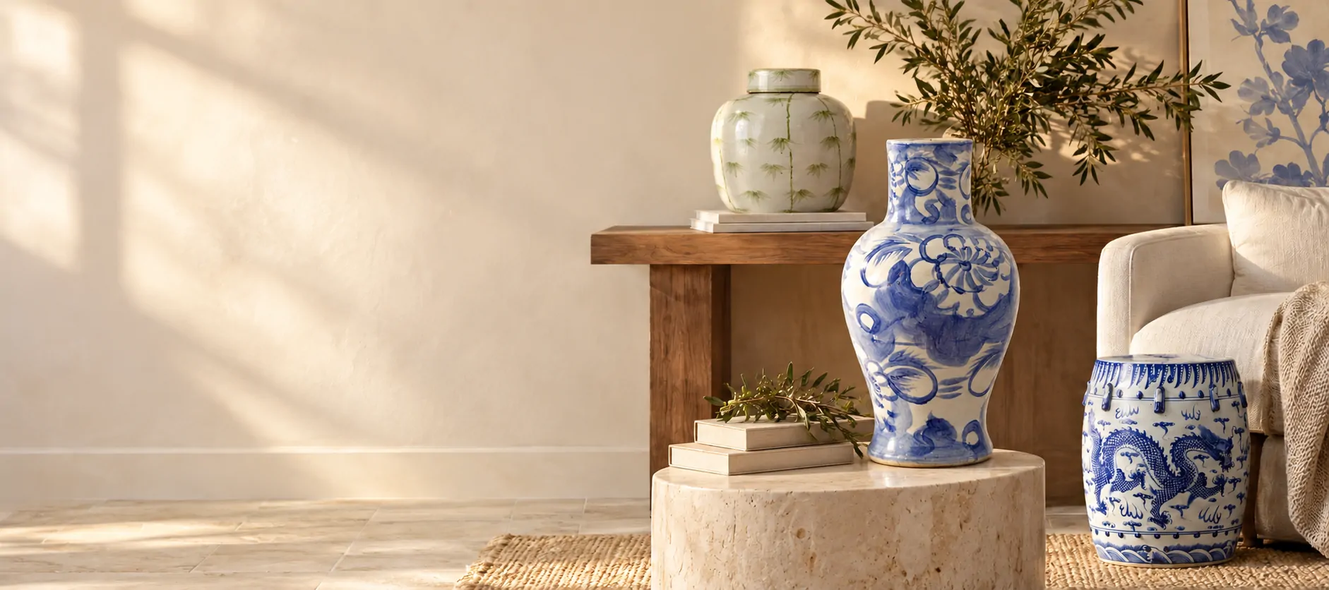 Blue-and-white porcelain vase, moss-green jar, and dragon-motif garden stool styled in a sunlit interior