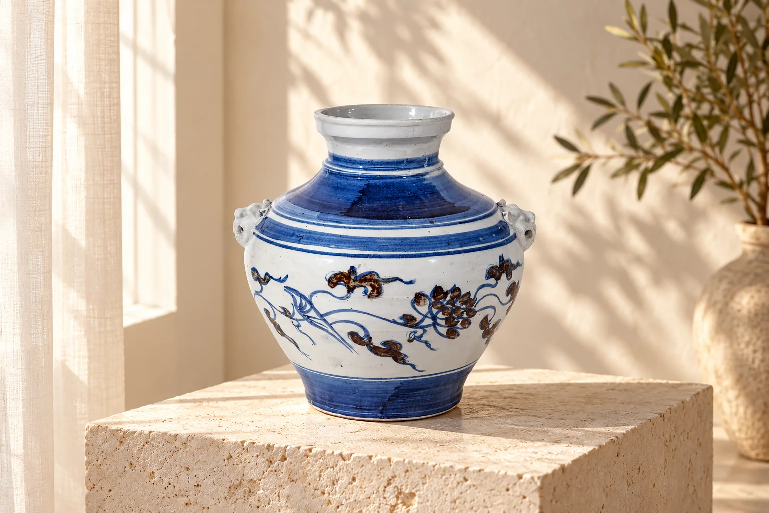 Blue-and-white lion-handle porcelain jar styled on a limestone plinth in a sunlit room