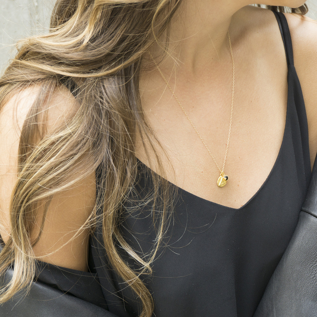 gold 'explore' charm necklace with black onyx stone detail
