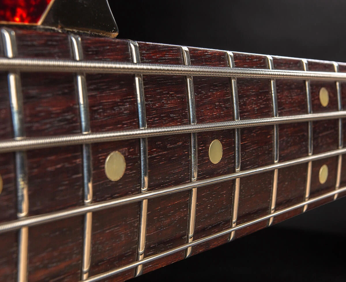 The strings of a four-string bass running the length of the fretboard toward the headstock.