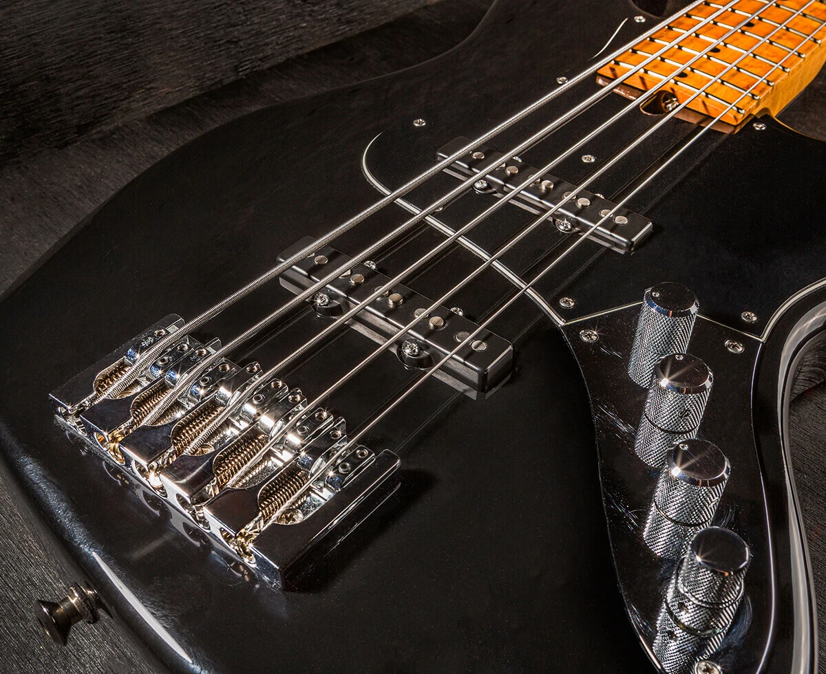 The strings of a five-string bass running the length of the fretboard toward the headstock.
