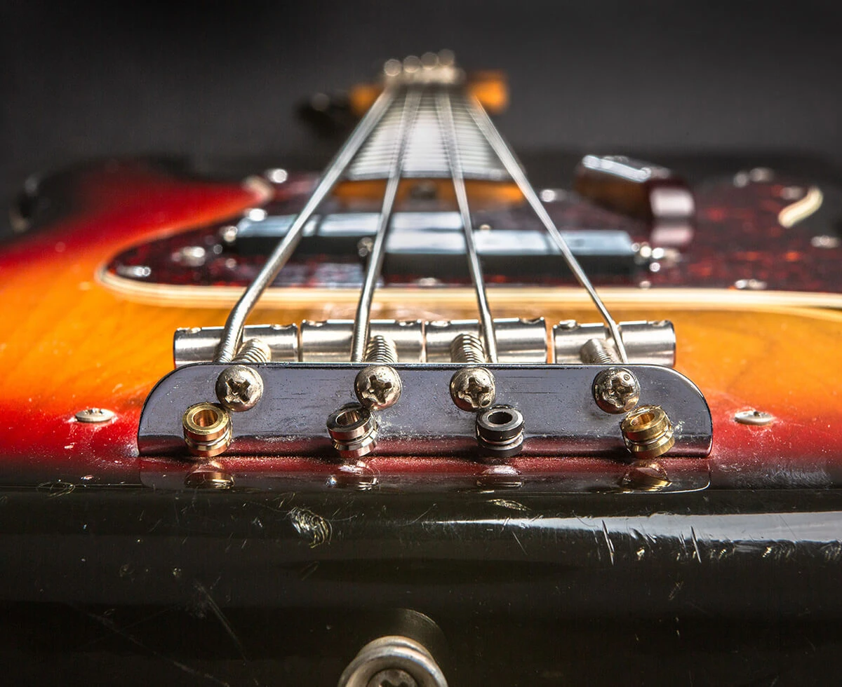 Front view of a four-string bass bridge with the strings anchored over the saddles. 
