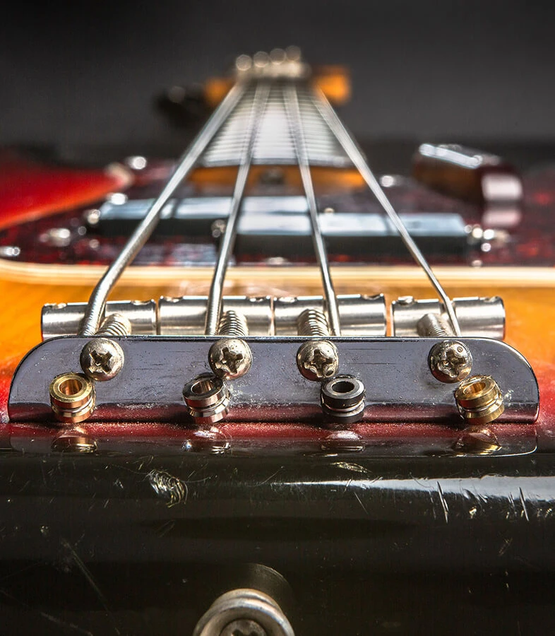 Front view of a four-string bass bridge with the strings anchored over the saddles. 