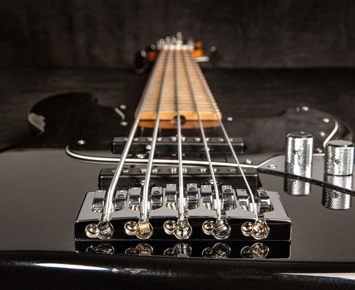 The strings of a five-string bass anchored at the bridge saddles.