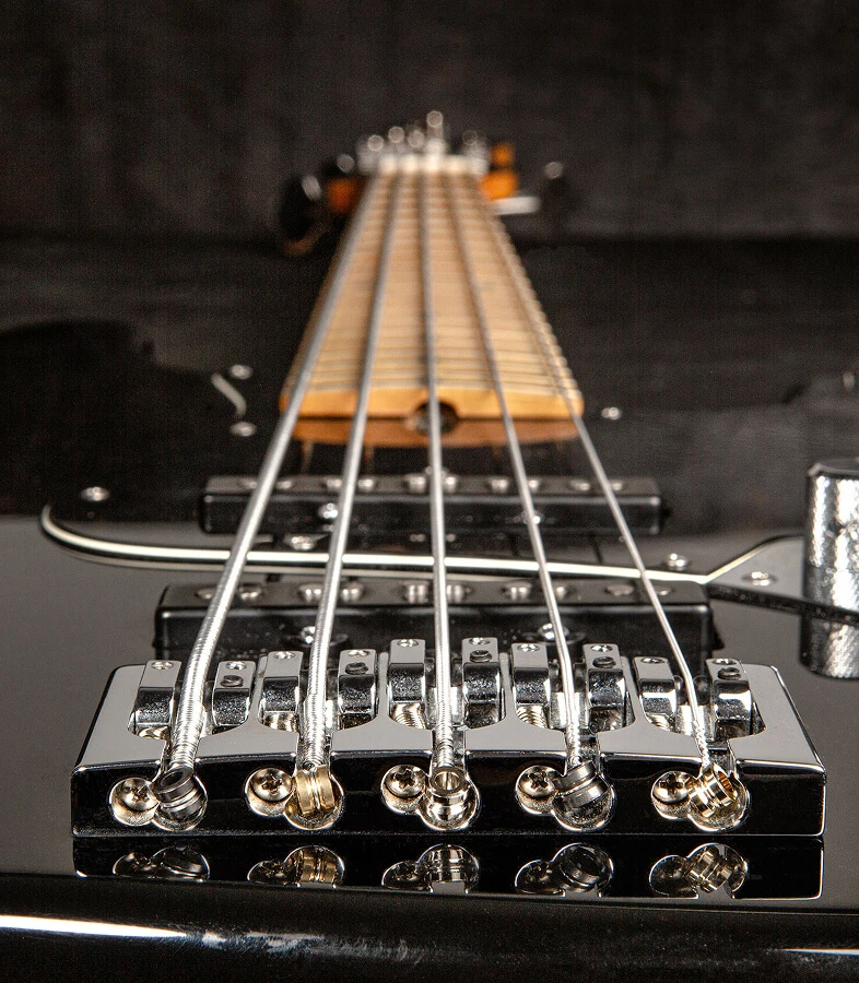 The strings of a five-string bass anchored at the bridge saddles.