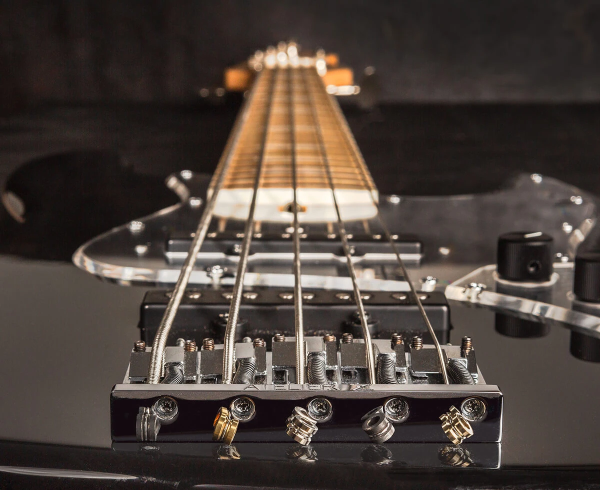 The strings of a five-string bass anchored at the bridge saddles.