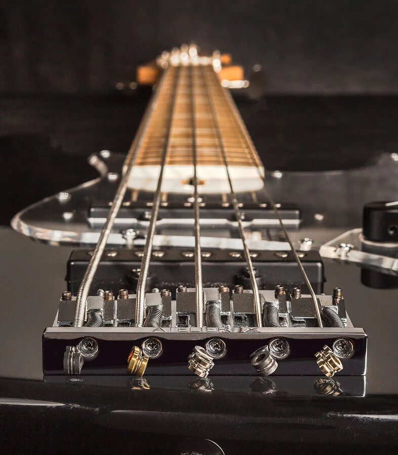 The strings of a five-string bass anchored at the bridge saddles.
