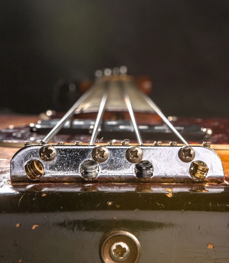 The strings of a four-string bass anchored at the bridge saddles.