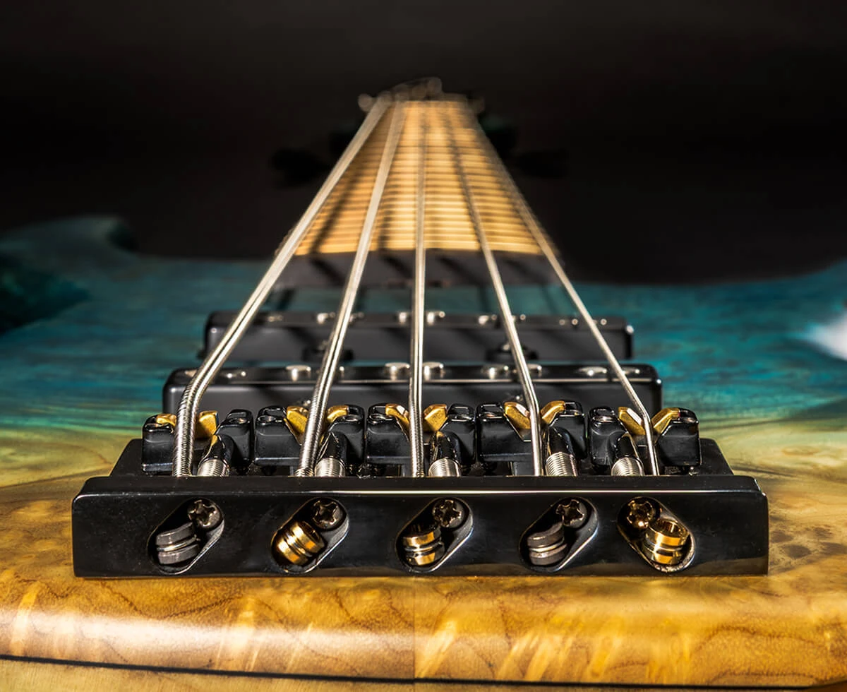 The strings of a five-string bass anchored at the bridge saddles.